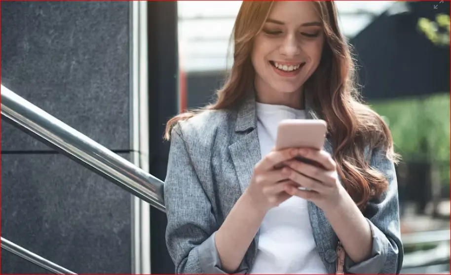 Persona concentrata mentre guarda lo schermo dello smartphone in penombra, riflettendo su un messaggio ricevuto in chat