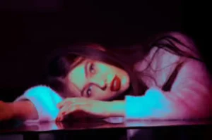 Primo piano sensuale di una modella in stanza buia illuminata da riflessi neon viola e fucsia