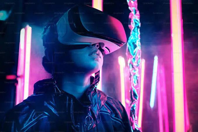 Modella sensuale che utilizza un visore di realtà virtuale in una stanza tecnologica illuminata da neon led colorati